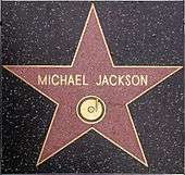Pink star with a gold colored rim and the writing "Michael Jackson" in its center. The star is indented into the ground and is surrounded by a marble-colored floor.