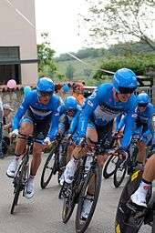 A group of cyclists wearing the same blue and black uniform while riding bikes.