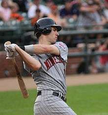 A baseball player in a pinstriped uniform follows through with a swing of a baseball bat.