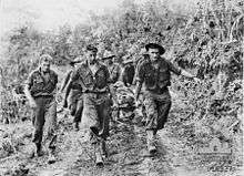 Soldiers carry a stretcher upon which another man lies