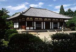 Wooden building on a stone platform with white walls.