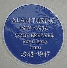 A Blue plaque on a white wall with the words "Alan Turing 1912–1954 CODE BREAKER lived here from 1945 – 1947