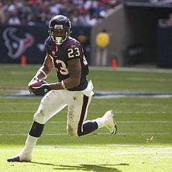  A football player running on a football field with a football