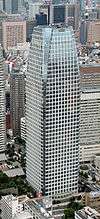 Aerial view of a glass, window-dotted high rise; the corners are cut near the top