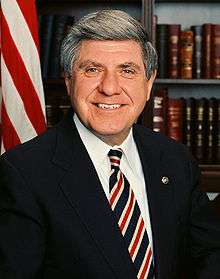 Man in business suit, American flag in background