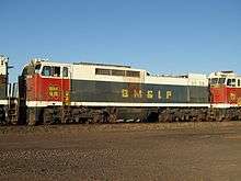 Broadside view of a boxy red, white, and black locomotive