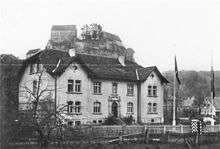 a black and white photograph of a building with a mountain behind it