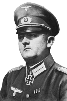 A man wearing a peaked cap and military uniform with an Iron Cross displayed at the front of his uniform collar.