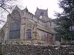 A large church seen from the southwest with a nine-light west window and a central tower set diagonally