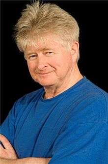 A man in a blue shirt in front of a black background