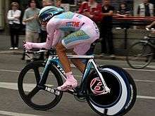 A cyclist wearing a pink skinsuit while riding a bike.