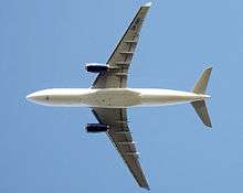 The undercarriage of an A330 have been retracted, showing an underside view of an A330 during flight. Under each wing is a turbofan engine.