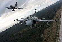  Three-quarter bottom view of two jet aircraft inn flight against a blue sky.