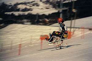 man sitting skiing down hill