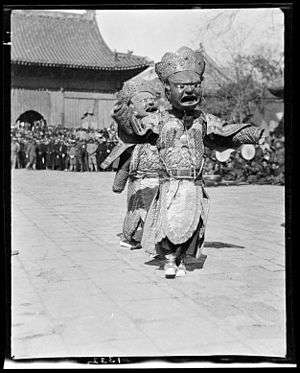 Two dancers in masks and costumes perform