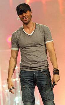 Enrique Iglesias, facing front, holding a microphone.