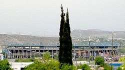 photo of stadium from outside with mountains in distance and trees in foreground