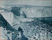 An onlooker looks out over an ice-covered bay in Antarctica.