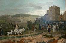 Jesus, riding a donkey colt, rides towards Jerusalem. A large crowd greets him outside the walls.