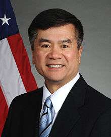 man in business suit, American flag in background