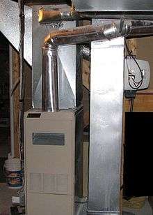 A photo of a modern forced-air gas furnace with associated ductwork nearby.