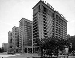 Large building with four tower sections rising vertically above the street.