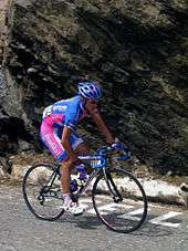 A cyclist wearing a blue and pink uniform while riding a bike.
