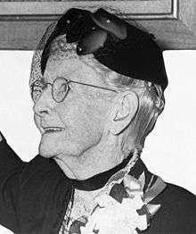 Grandma Moses, wearing eyeglasses and a fancy hat