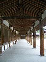 A semi-open wooden corridor with white walls.