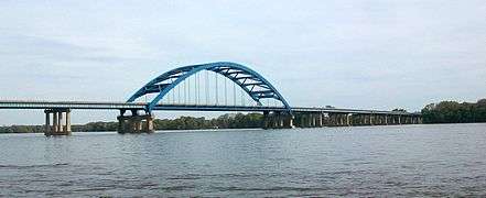 A bridge with a large arch crosses a river.