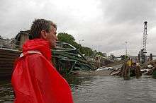 R.T. Rybak in a red poncho looking at the collapsed bridge in the water