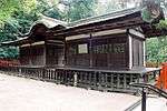 A wide wooden building with a passageway over which there is a Chinese style gable.