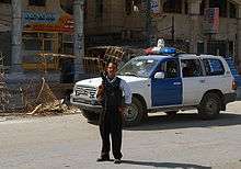 Police officer with gun in front of a police car