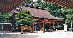Wooden building with raised floor, vermillion red beams and railed open veranda.