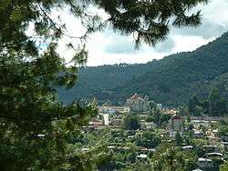 Distant view of the town, with a tree-covered mountain behind.