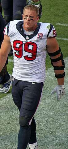  A Caucasian football player without his helmet on, walking down the sideline. Eyeblack is visible