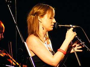 A side profile of a woman singing into a microphone on a stand.