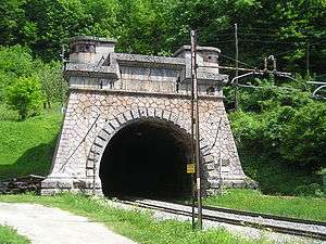 a colour photograph of a railway line running into a tunnel faced with masonry