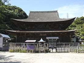 Large wooden building with and added enclosing pent roof.