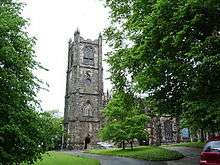 A church with a west tower surmounted by battlements and pinnacles