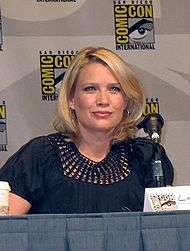 A woman with blonde hair sitting at a conference.