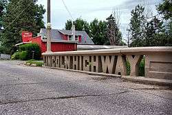 A small concrete bridge crosses a stream. The sides of the bridge were designed to spell out "Lincoln Highway".