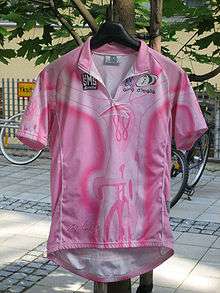 A pink jersey hung on coat-hanger, with bikes in the background