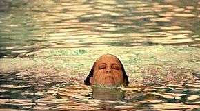 A woman emerging from a swimming pool.