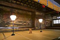 Tatami matted room with a large scale wall painting of a court scene.