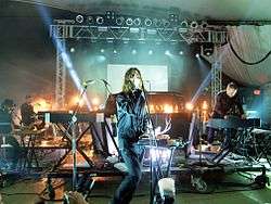 A blonde woman (Lykke Li) holds an off-screen microphone in a bar setting.