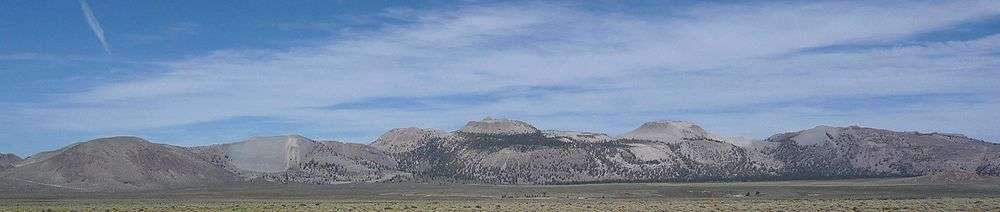 An overlapping series of gray domes with sharp peaks. Scrubland in foreground.