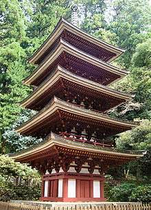 Wooden five-storied pagoda with white walls and red beams.