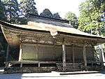A wooden building with slightly raised floor, a hip-and-gable roof and a canopy over the steps.