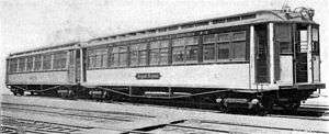 A photo of IRT Composite Prototypes. This photo is in black and white, and shows two wooden railcars, built circa 1902, on some railroad tracks.